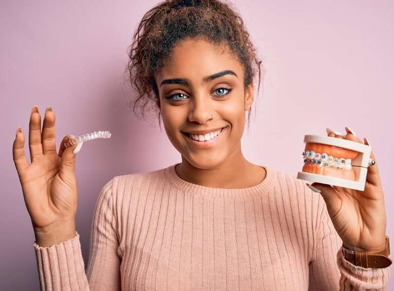 woman holding Invisalign and a dental mold with braces