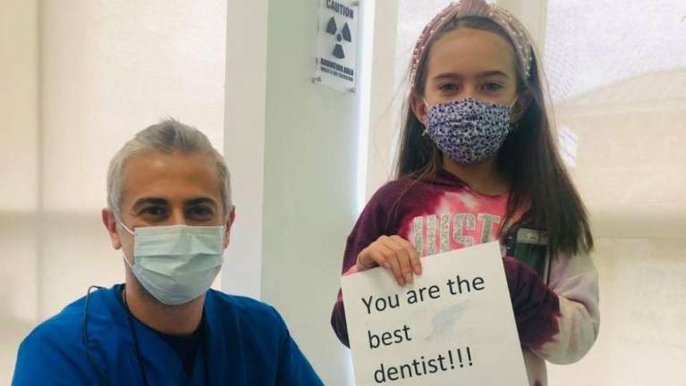 young girl standing next to dentist