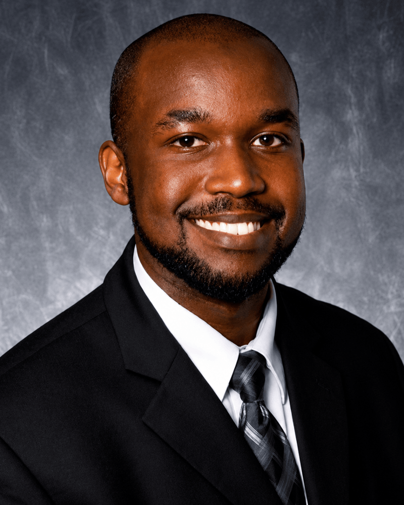 Dr. Hussam Ahmed, endodontist, smiling confidently in professional headshot wearing dark suit and tie